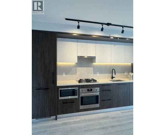 A modern kitchen with dark wood cabinets and stainless steel appliances.