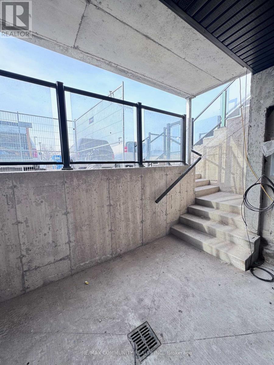 A concrete room with a staircase and a window overlooking a construction site.