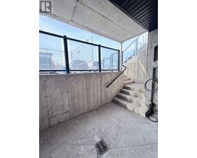 A concrete room with a staircase and a window overlooking a construction site.