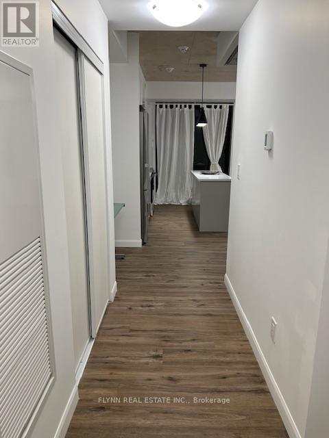 A long, narrow hallway with wood flooring and white walls.