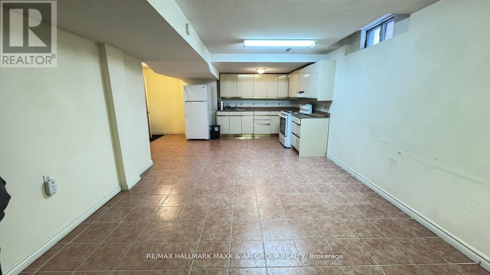 A large, empty room with a kitchen area in the background.