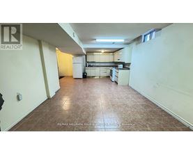 A large, empty room with a kitchen area in the background.