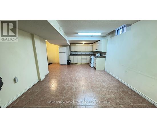 A large, empty room with a kitchen area in the background.