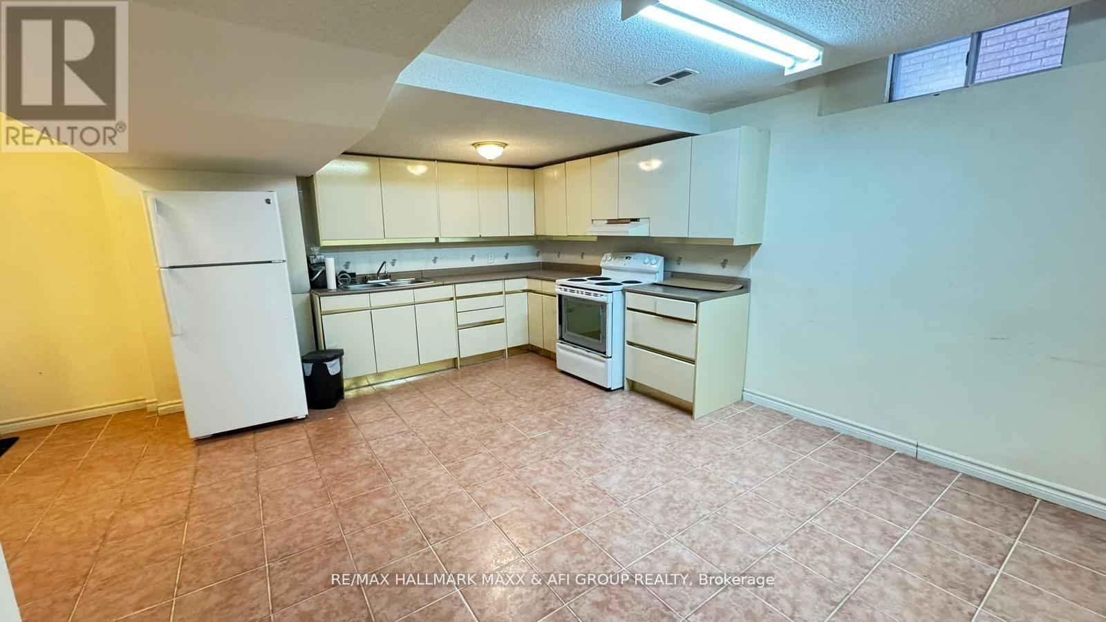 A kitchen with white appliances and brown tile flooring.