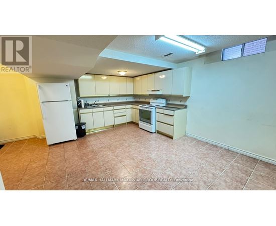 A kitchen with white appliances and brown tile flooring.