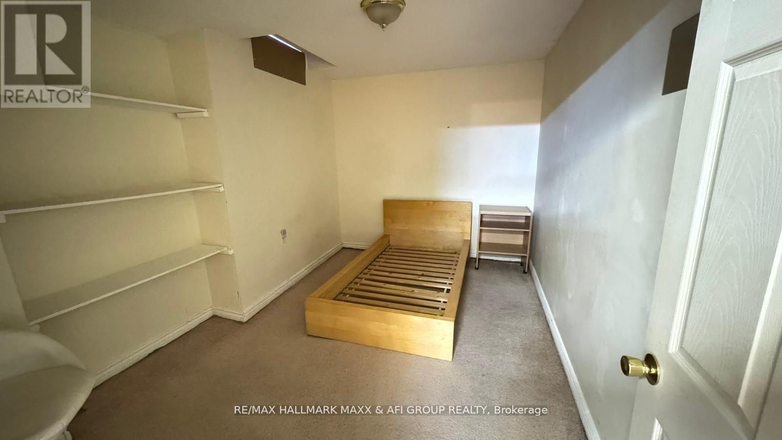 A bedroom with a bed, shelves, and a door.