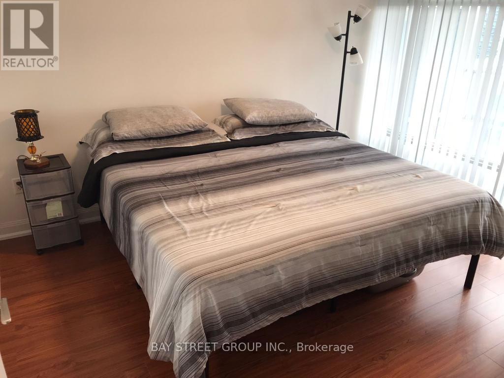 A bedroom with a large bed and a nightstand with a lamp.