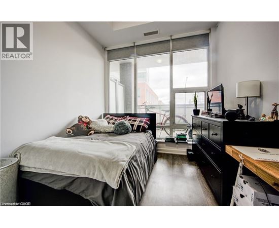 A bedroom with a bed, dresser, and window.
