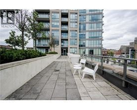 A balcony with two chairs and a table is in front of a building with the word REALTOR on it.