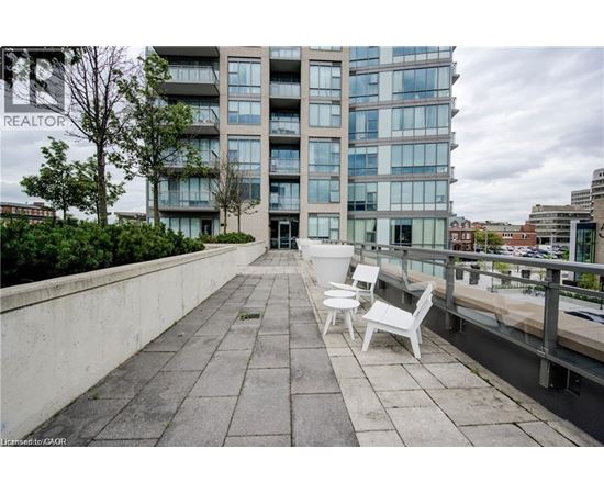 A balcony with two chairs and a table is in front of a building with the word REALTOR on it.