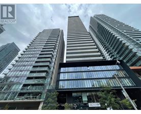 A tall building with a glass facade stands in front of other skyscrapers.