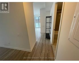 A hallway with wood flooring and white walls, leading to a door with a black frame.