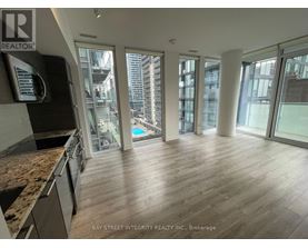 A spacious room with wooden flooring and large windows overlooking a cityscape.