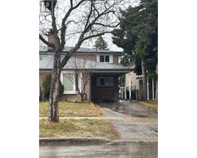 A house with a grey roof and a tree in front of it.