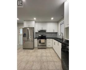 A kitchen with white cabinets and a black countertop.