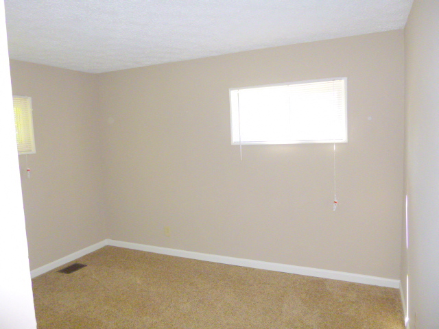 an empty room with a window and a carpet