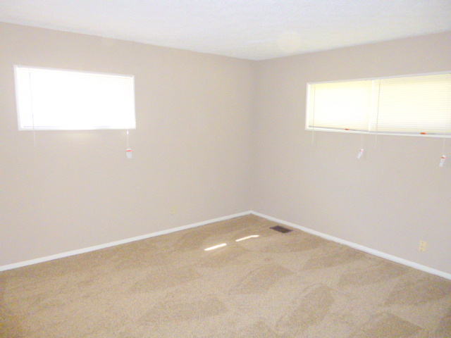 an empty room with two windows in it