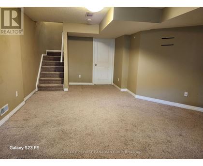 A spacious room with a staircase leading to the upper level.