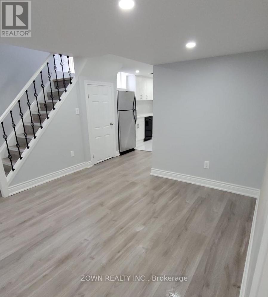 A spacious room with wood flooring and white walls.