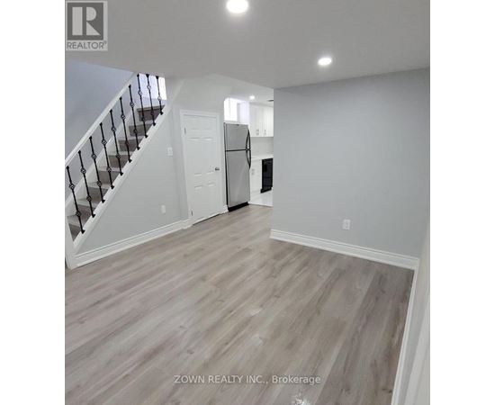 A spacious room with wood flooring and white walls.
