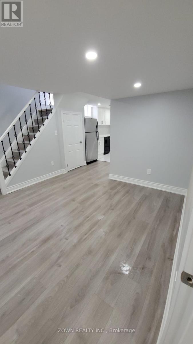 A spacious room with a staircase and a door in the background.