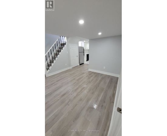 A spacious room with a staircase and a door in the background.