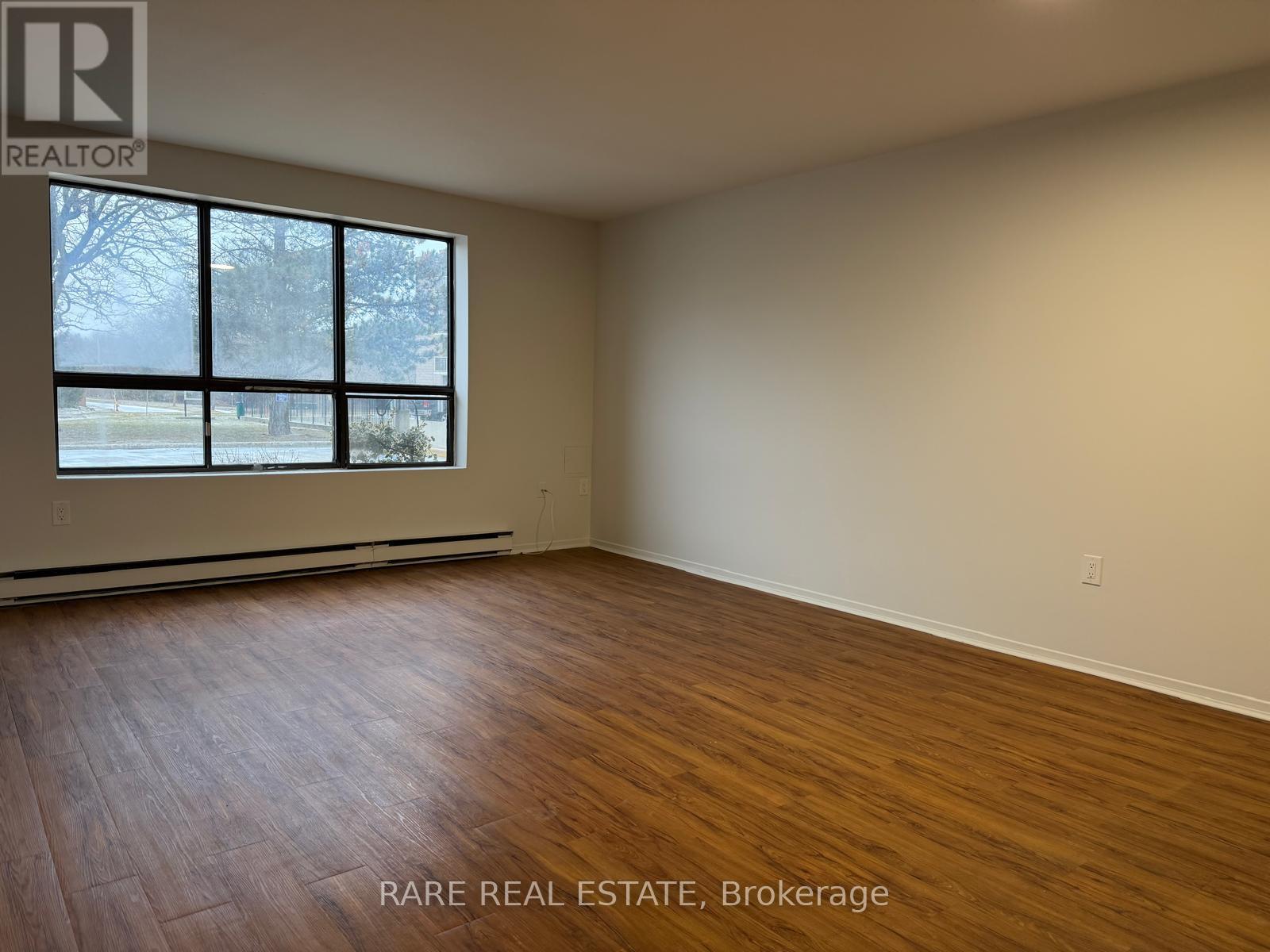 A room with wooden flooring and a large window.