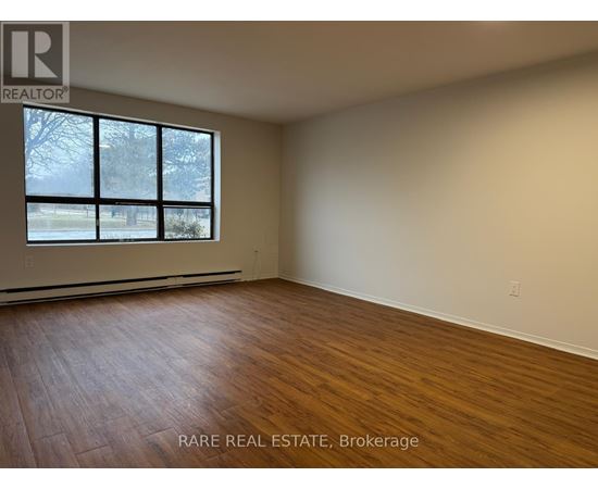 A room with wooden flooring and a large window.