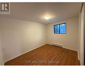 A room with a window and a wooden floor.