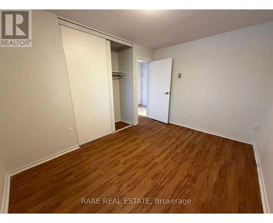 A room with wooden flooring and white walls, with a door on the right and a closet on the left.