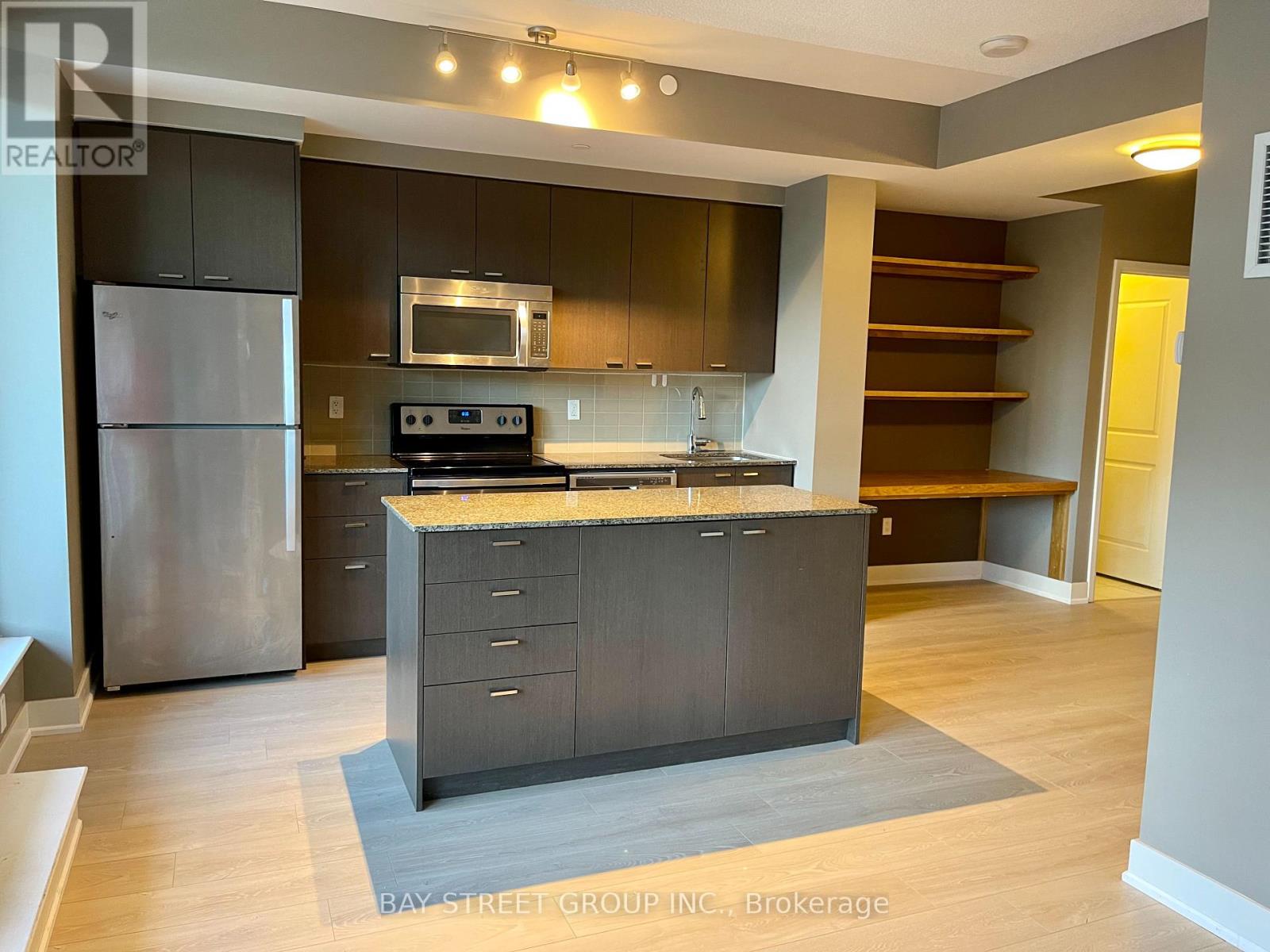 A modern kitchen with dark wood cabinets and stainless steel appliances.