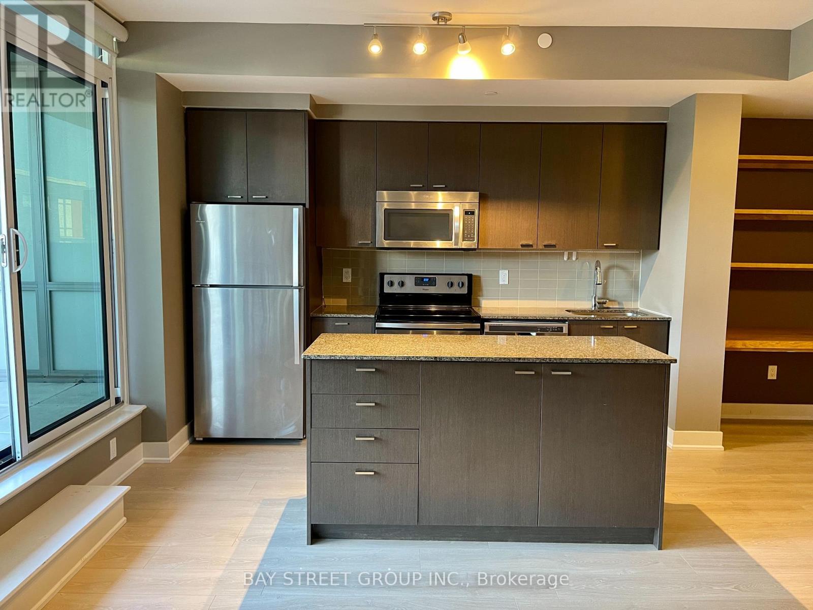 A modern kitchen with a refrigerator, microwave, oven, and sink.