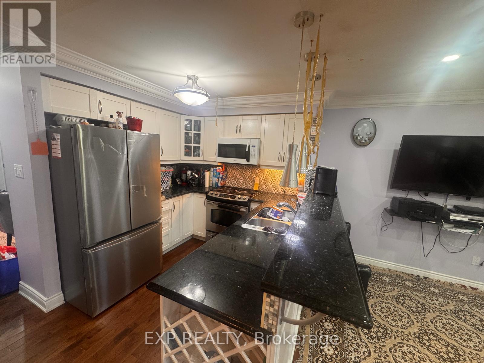 A kitchen with a black counter top and a refrigerator.