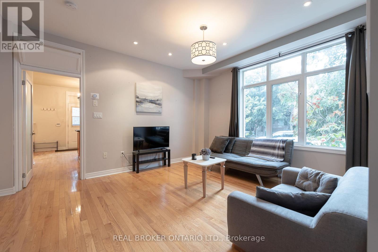 A living room with a grey couch and a wooden floor.