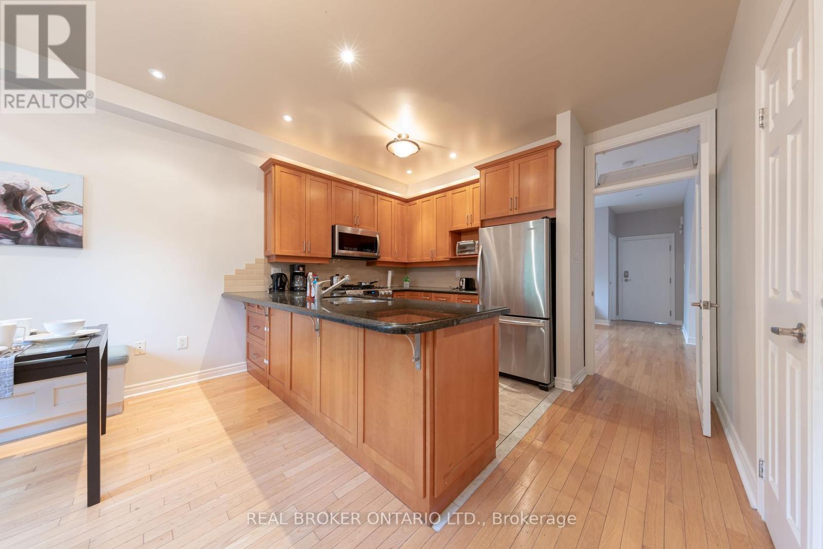 A kitchen with wooden cabinets and a stainless steel refrigerator.