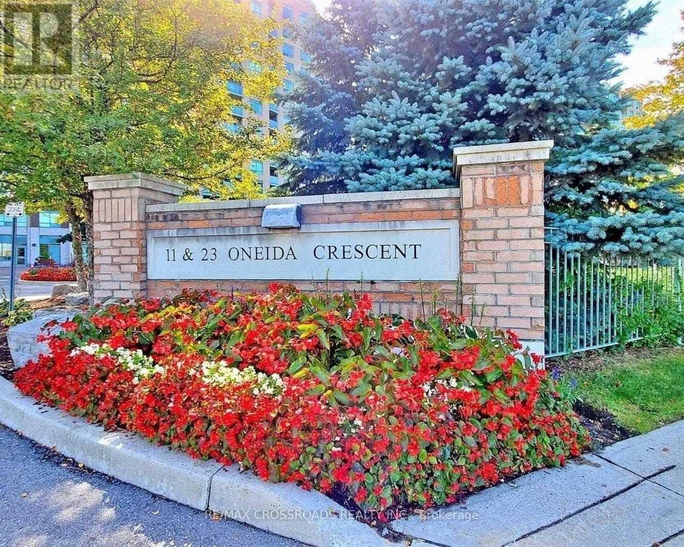 A sign that reads "11 & 23 Oneida Crescent" is surrounded by red flowers.