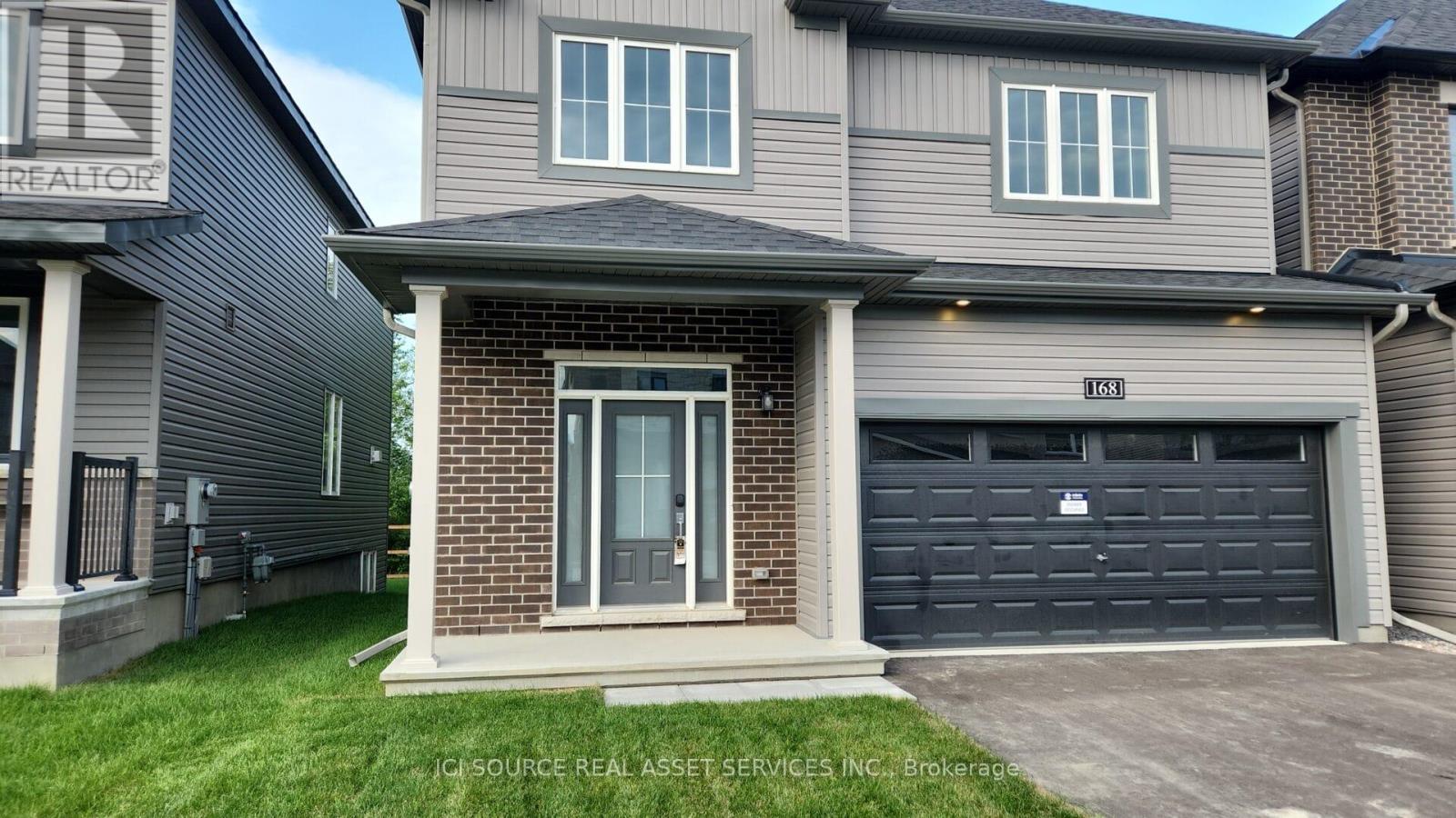 A house with a grey garage door and a brick wall.