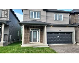 A house with a grey garage door and a brick wall.