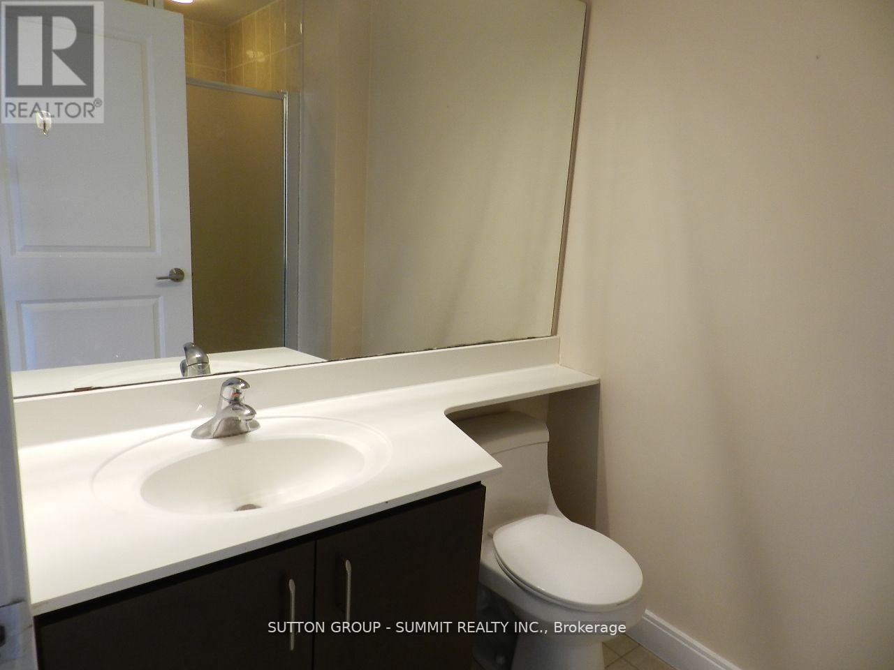 A white sink in a bathroom with a toilet in the corner.