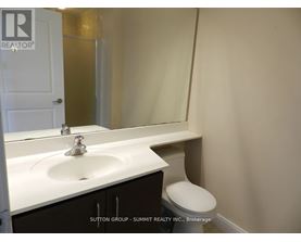 A white sink in a bathroom with a toilet in the corner.