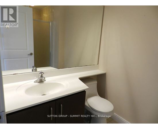 A white sink in a bathroom with a toilet in the corner.