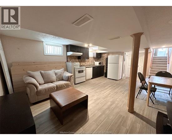 A living room with a couch, a coffee table, and a kitchen area in the background.