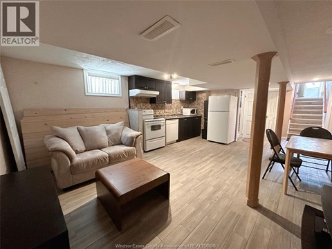 A living room with a couch, a coffee table, and a kitchen area in the background.