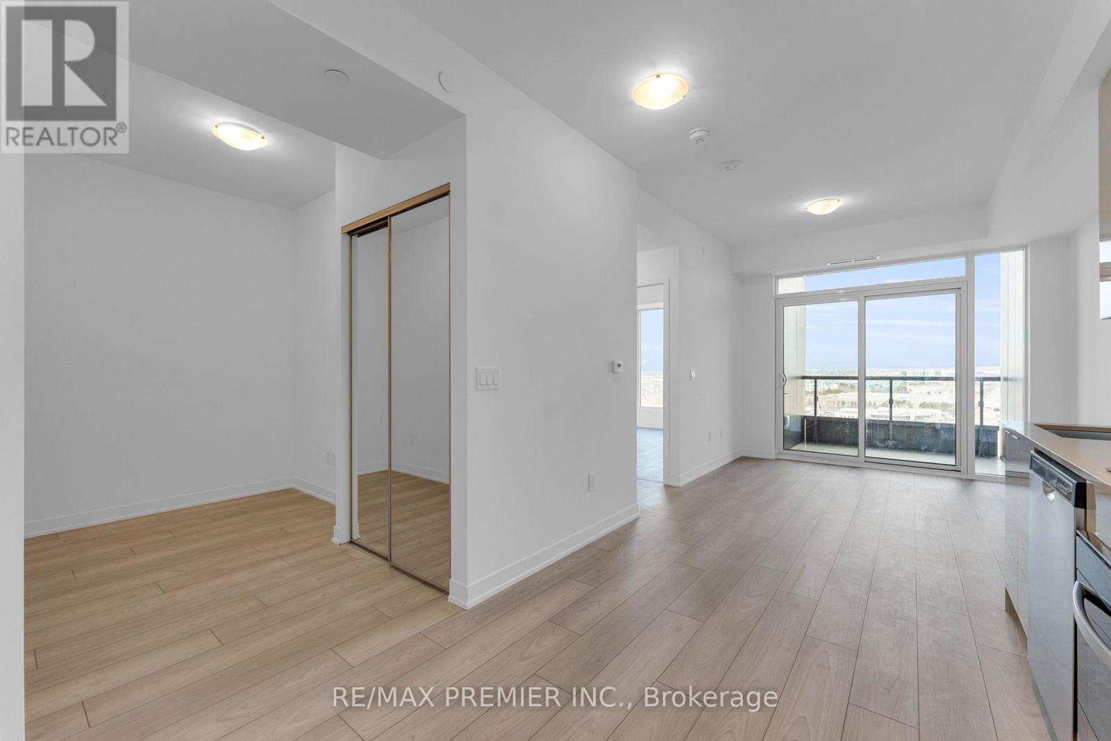 A spacious room with wooden flooring and a sliding glass door leading to a balcony.