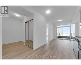 A spacious room with wooden flooring and a sliding glass door leading to a balcony.