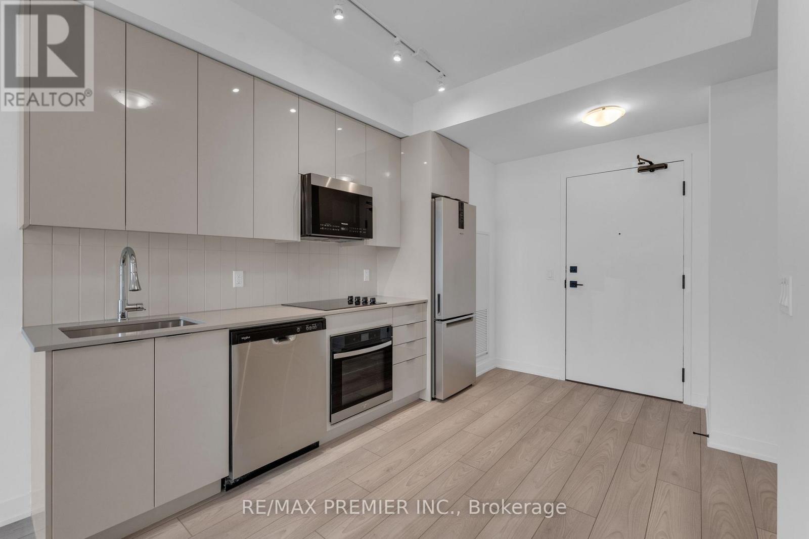 A modern kitchen with beige cabinets and stainless steel appliances.