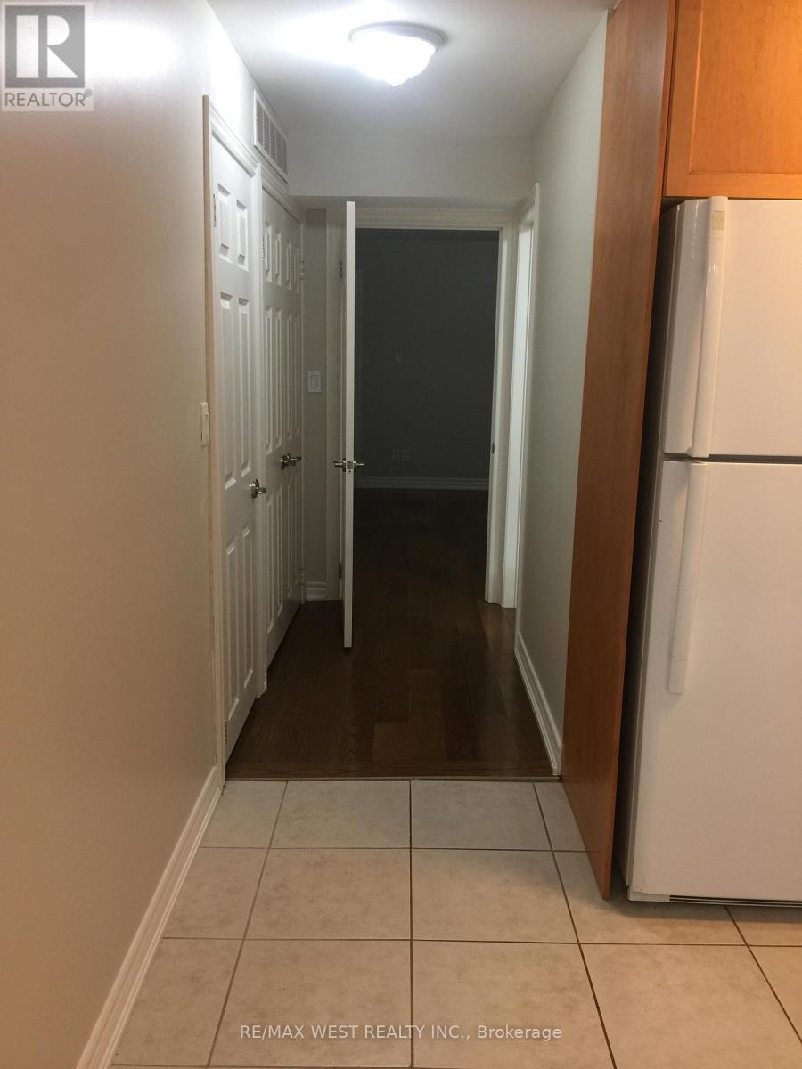 A hallway with a white refrigerator on the right.