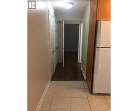 A hallway with a white refrigerator on the right.