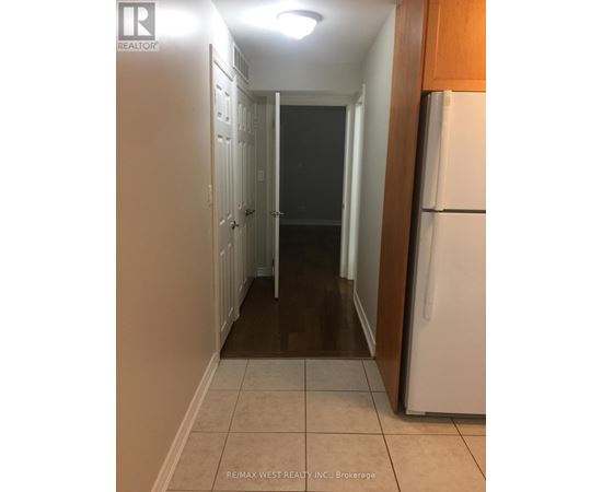 A hallway with a white refrigerator on the right.