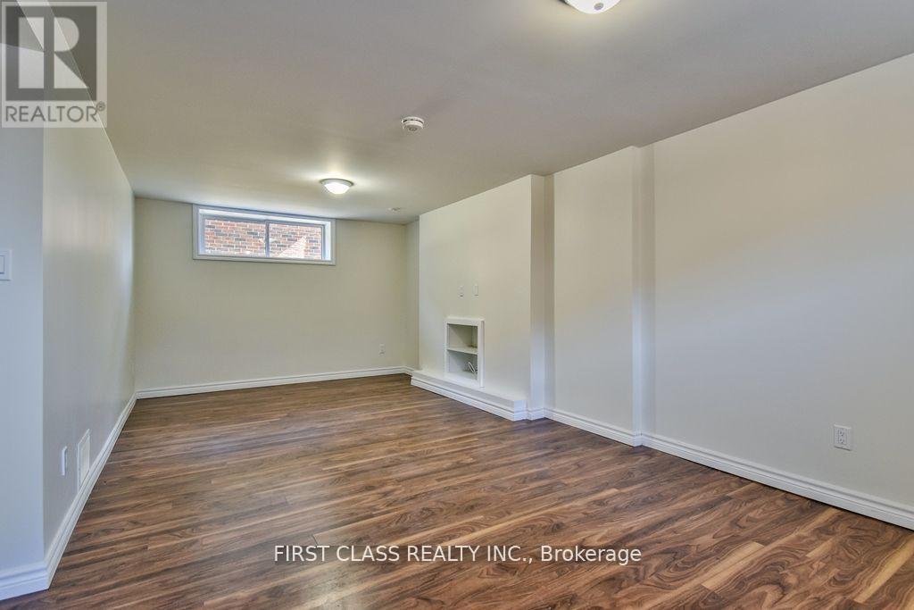 A room with wooden flooring and a window with a view of a building.